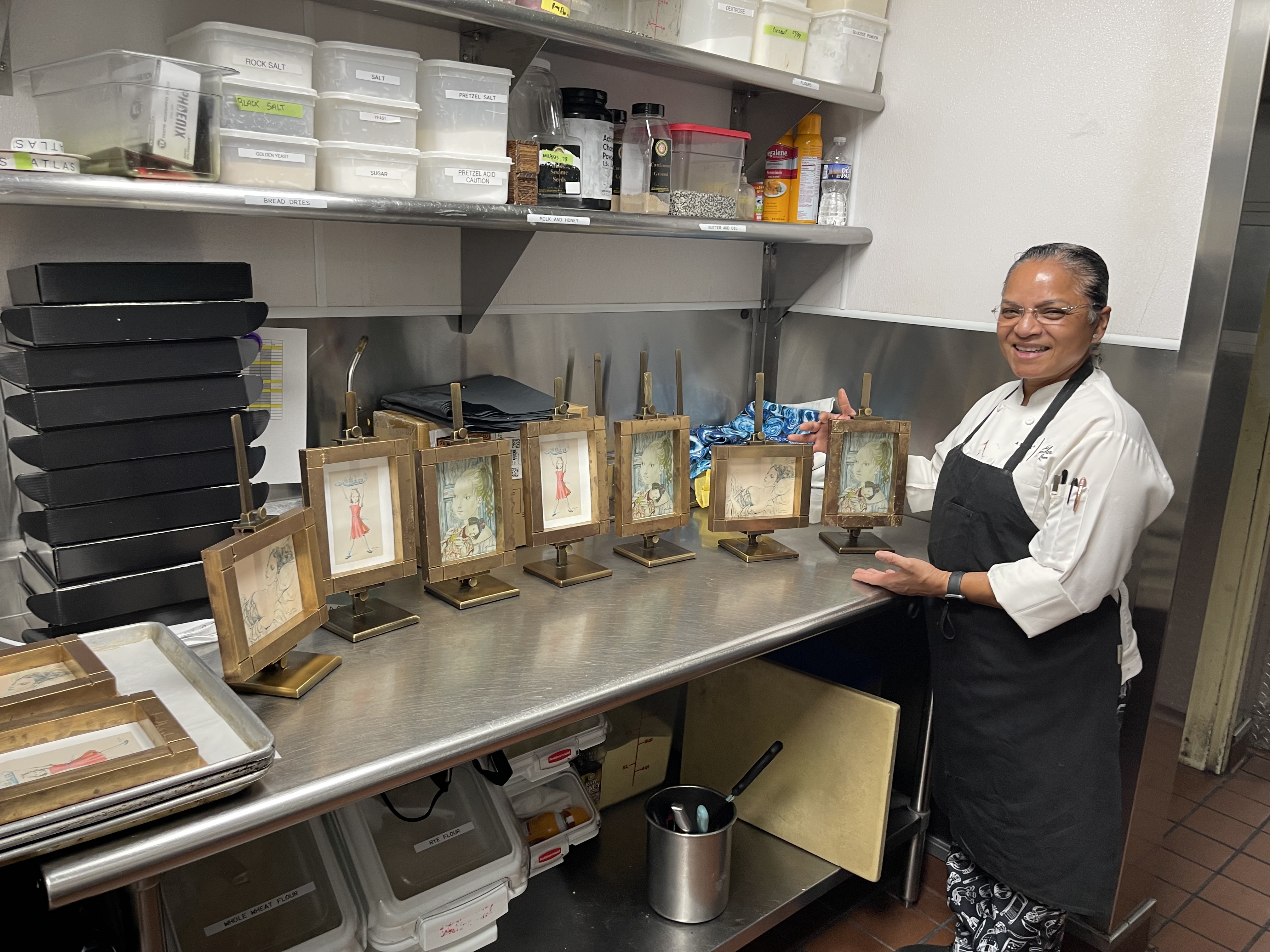 Charito standing beside handcrafted chocolate frames in the pastry kitchen